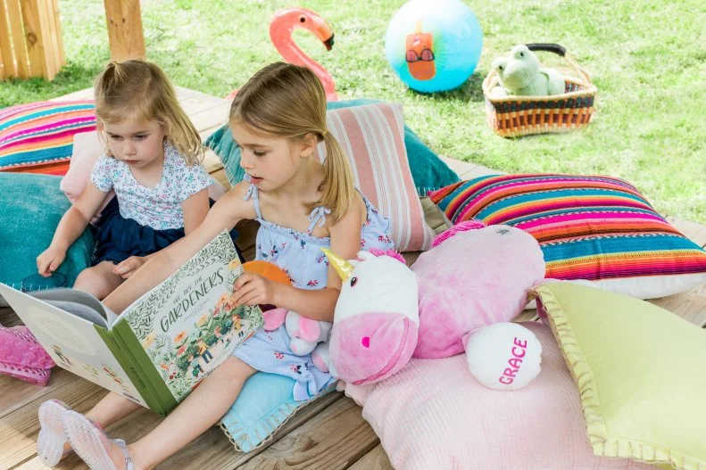 The hangout space below the elevated shed structure is used as a shaded space for Grace and River to read books.