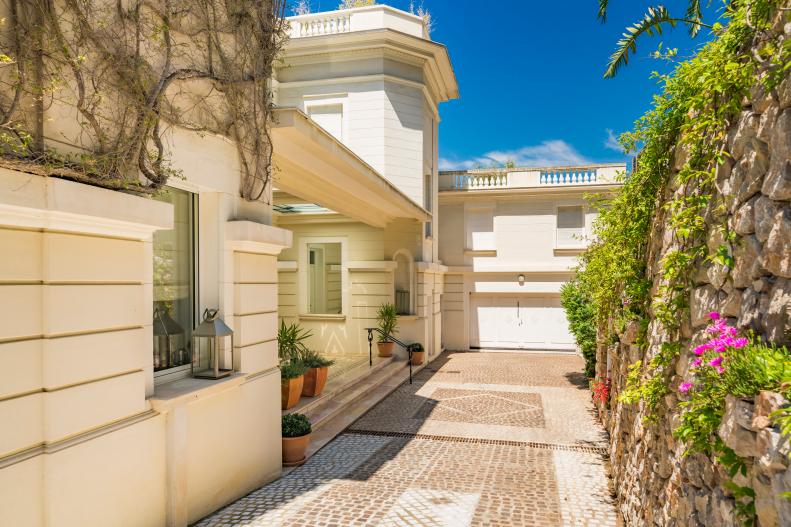 The dramatic driveway entrance with its lush Mediterranean plant life and spectacular stone wall leads to the private entrance of this South of France villa that feels at every turn like a private oasis fit for a movie star.