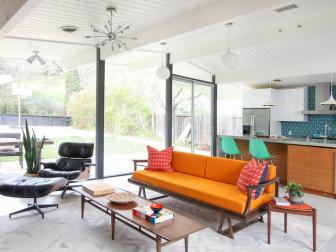 This family room features an orange sofa and black Eames chair.