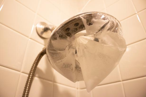 Plastic bag with cleaner secured around a showerhead.