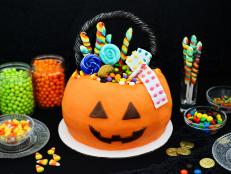 Inspired by the classic pumpkin-shaped candy carrier, this treat-filled Halloween cake is a not-too-spooky yet oh-so-fun way to ring in the season. The round jack-o'-lantern shape is made easily from two bundt cakes stacked together and frosted.
