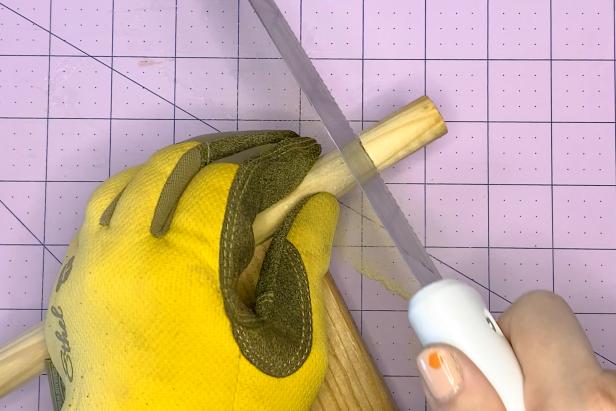 Using a hand saw, and wearing protective gloves, slowly cut the piece of pine trim at the measured pencil mark.