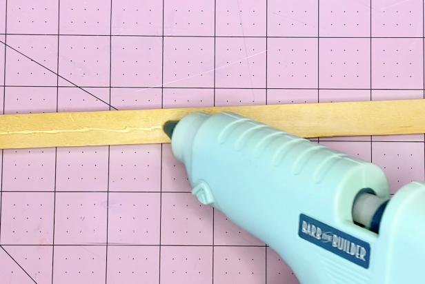 Using a low temp hot glue gun, apply a thin line of glue along the back side of the pine trim. This will secure the magnet strip.