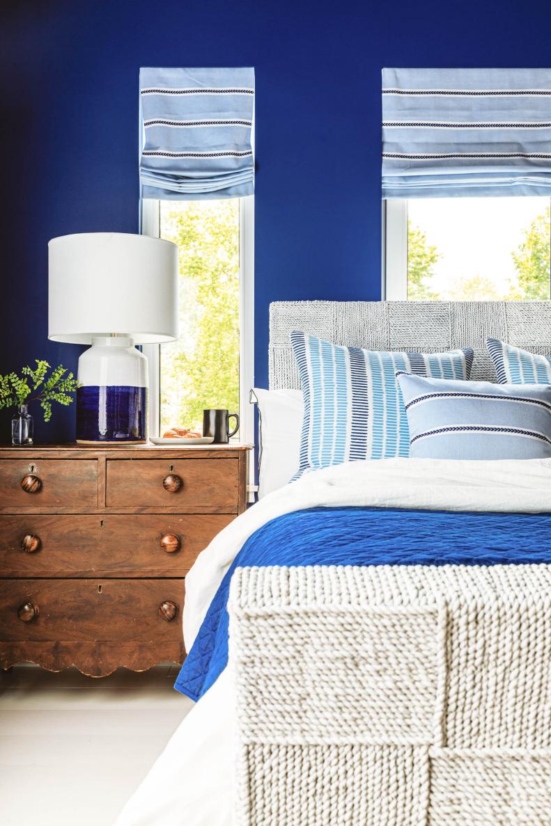 Bed With Blue Linens Next to Vintage Wood Dresser Nightstand
