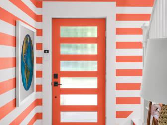Panes of Glass in Orange Front Door Echoes Striped Wallpaper in Foyer