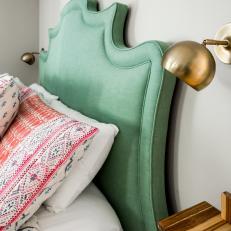 Green Upholstered Headboard and Gold Sconces