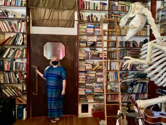 A homeowner poses in her library with a dinosaur skeleton.