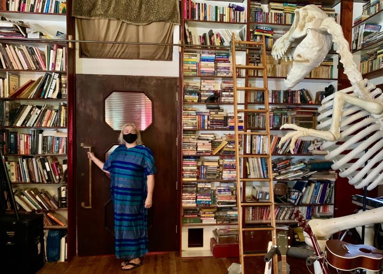 A homeowner poses in her library with a dinosaur skeleton.