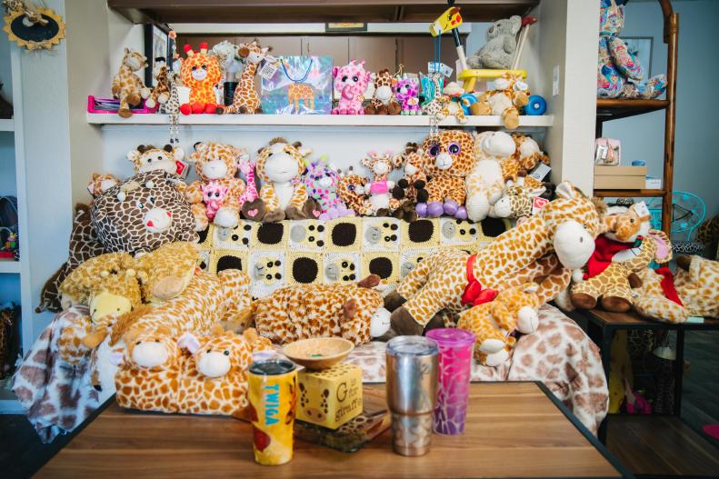A living room features giraffe prints and stuffed animals.