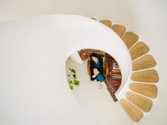 A homeowner poses at the foot of a sculptural spiral staircase.
