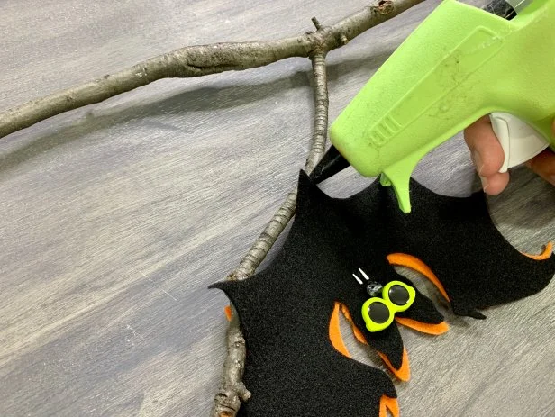 Find a fallen branch and trim down to fit your space. Glue the bats upside down on the branch with a hot glue gun.