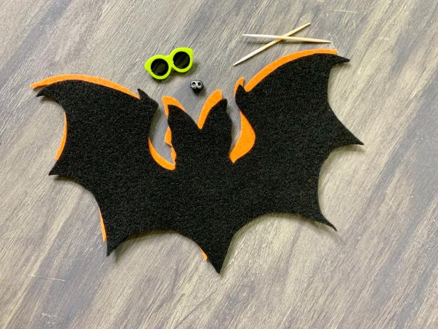 With a pair of wire cutters, cut off the backside of the miniature sunglass button so they will lie flat. Glue the glasses on the center of the face of the black felt bat with a hot glue gun. Hot glue the nose directly underneath the glasses. TIP: No mini sunglasses? Use two beads instead. No animal nose? Use a button or cut an upside-down triangle out of felt.