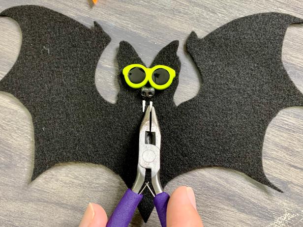 Add a small dab of felt glue on a piece of scrap paper. Grab each fang with the wirecutter and lightly dip into the glue. Glue them in place splitting center underneath the nose.