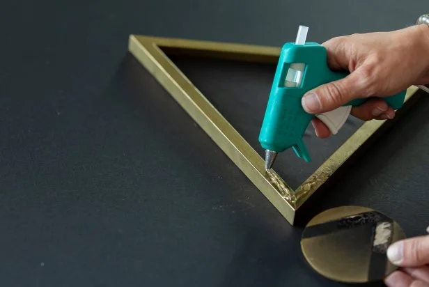 Use a low temp hot glue gun to adhere the wooden circle to the outside of the frame.