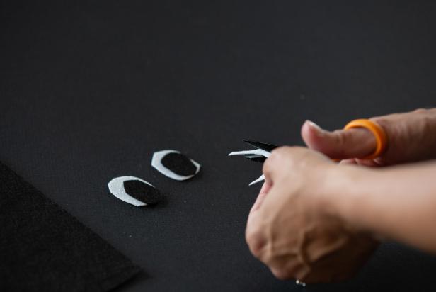 Use scissors to cut out eye shapes and a mouth from black and white pieces of felt.