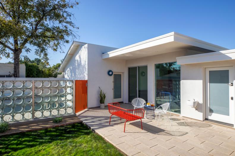 This midcentury modern home features a swimming pool and red gate.