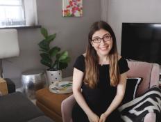 Woman Smiles at Camera Sitting on Pink Chair in Apartment Living Room