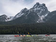 Kayakers paddle on a lake beside the Grand Tetons.