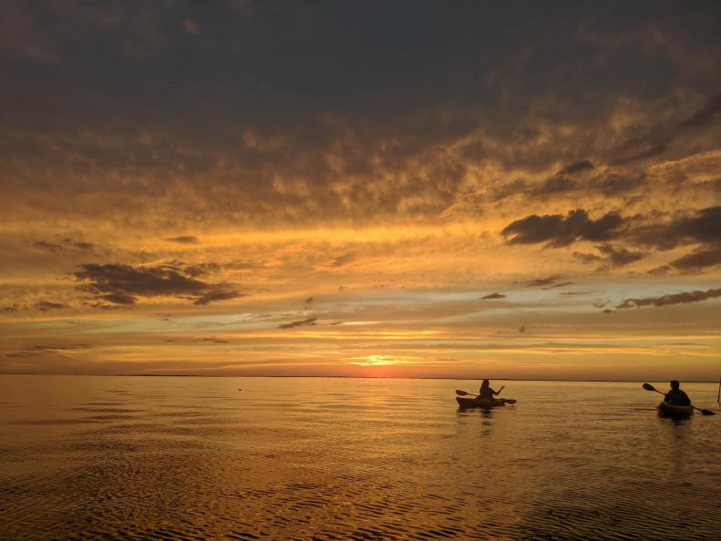 Kayakers paddle on the Gulf of Mexico at sunset. 