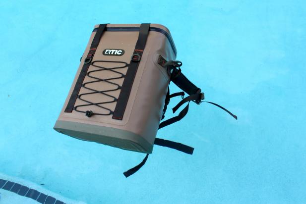 Brown and dark green RTIC Cooler Backpack floating in swimming pool