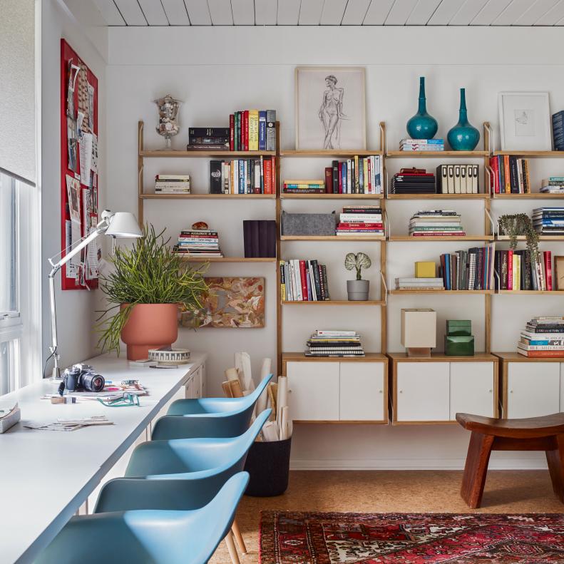 This office includes a shelving unit and midcentury chairs.