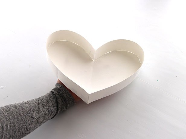 Using tape, attach the strips of paper to the edge of one of the paper hearts. Continue adding strips all the way around the edge.
