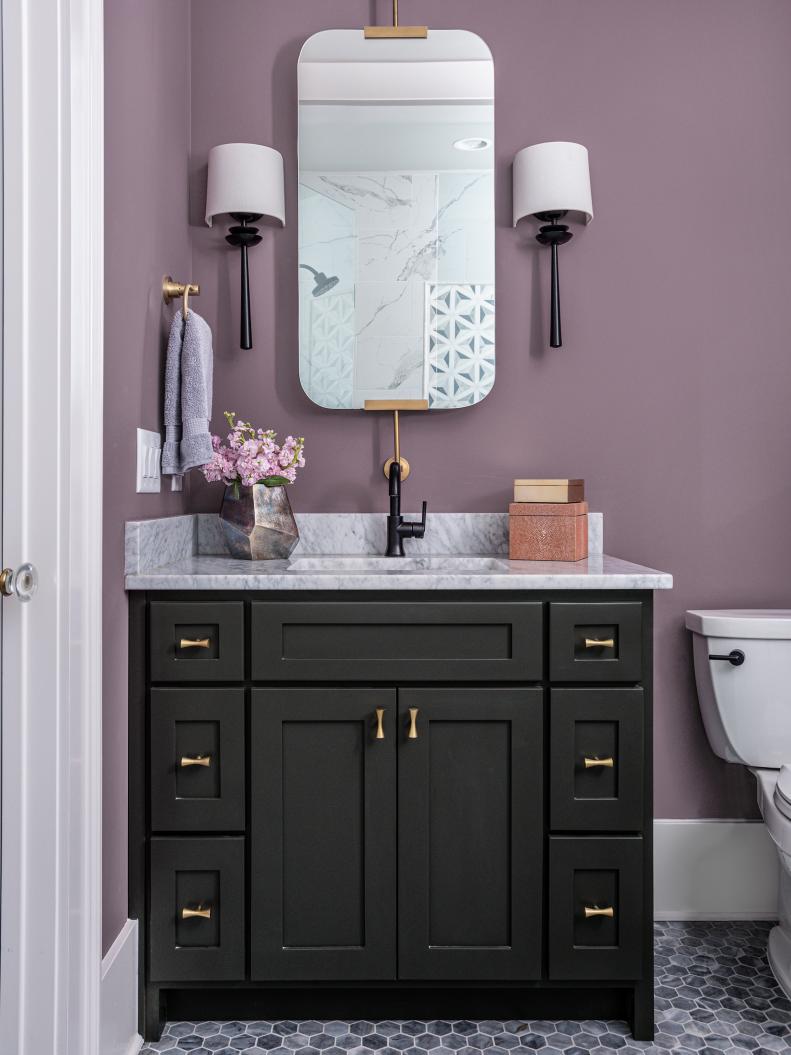 Romantic—but make it modern, requested the Nashville, TN, homeowners. Designer Beth Haley had their vanity painted dark gray and the walls deep lavender (Soulmate by Sherwin-Williams), then mixed in black and brass finishes. “A faceted vase always adds sophistication,” she says.