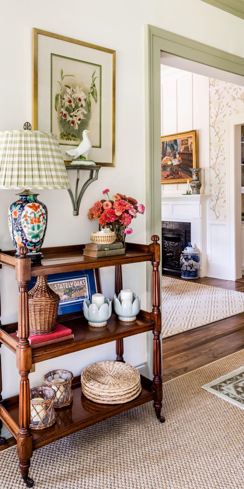 White hall with sisal area rug and wooden shelving with antiques. 