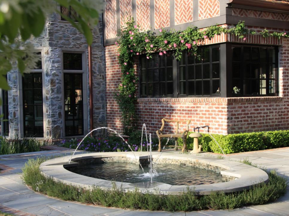 Fountain and Rose Covered Wall On Tudor Home 