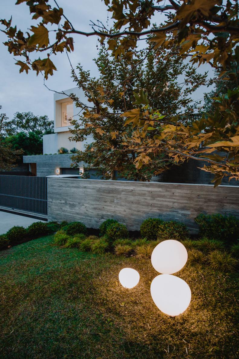 Glowing Orbs in Landscaping at Modern Home With Black Fencing