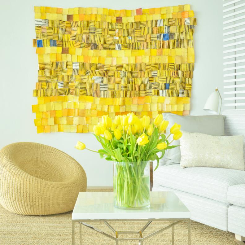 This living room features a yellow tapestry and rattan chair.