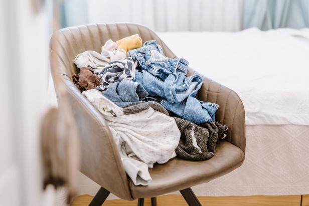 A chair is piled high with dirty clothes.