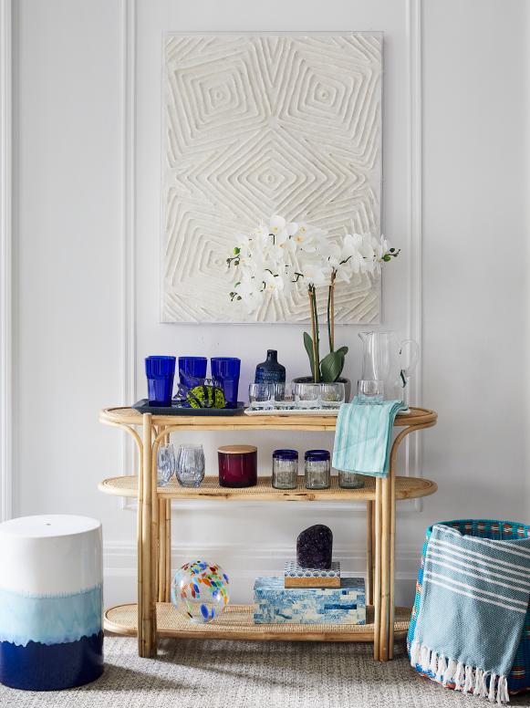 A wicker bar cart decorated with blue accessories by designer Lilly Bunn.