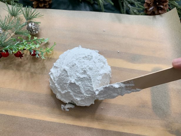 Add a snowy look to round half floral foam with textured snow paint. Use a lot of paint and apply it to the foam with a craft stick for a truly organic look. Once done, add a sprinkle of glitter for some extra sparkle. Tip: If you have trouble finding textured snow paint add baking soda to acrylic paint for some texture.