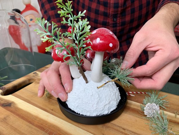 Place the floral ball inside the base of the cloche. Press the mushrooms on top of the floral foam by sticking in the toothpicks until the stem meets the snow. Add other wintery faux flashes to really complete the look, add the glass, and enjoy!