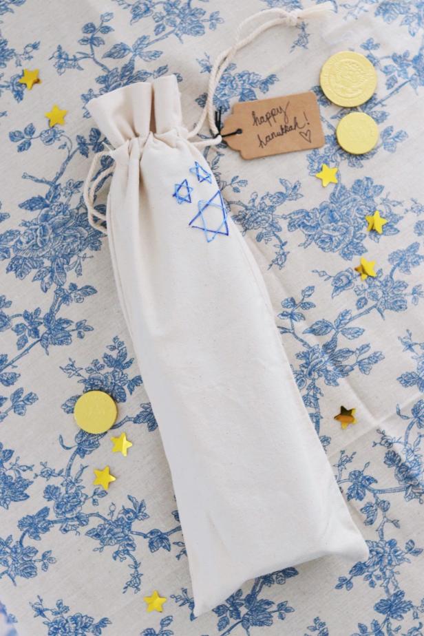 Linen Gift Bag With Embroidered Blue Stars and Gift Tag That Reads "Happy Hanukkah"