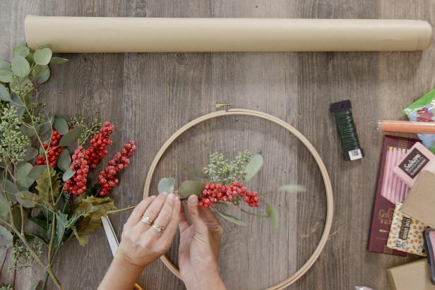 Hold one of each type of greenery together and wrap the stems with floral wire to create small bundles. Then wrap the floral wire around the embroidery hoop to secure the bundle in place. Repeat with three or four bundles.