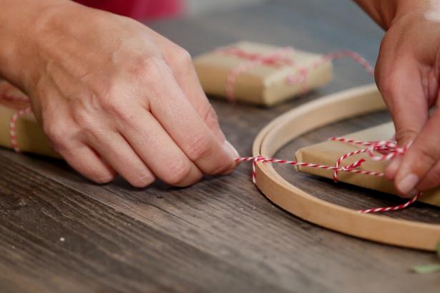 Tie bakers twine around each gift and then onto the embroidery hoop. Be sure to vary the lengths of string so the gifts hang at different heights.