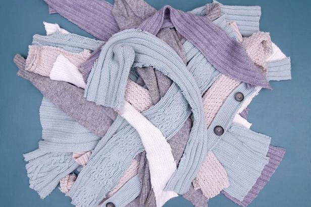 Gather old and unusable sweaters. Lay each one flat and cut vertical strips up the center.