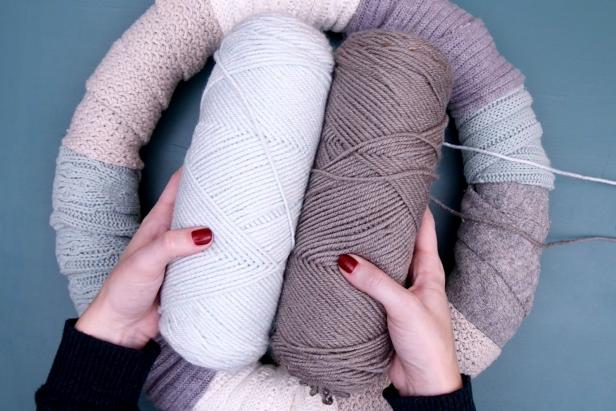Tie yarn onto the wreath and wrap it around in a random pattern. Repeat with a second color of yarn that matches your sweaters. Tie off and trim the excess.