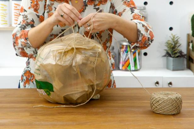Wrap twine around the bag, pulling it tight to give the bag ribbed sections, like a pumpkin. Tie the ends of the twine so it’s secure.