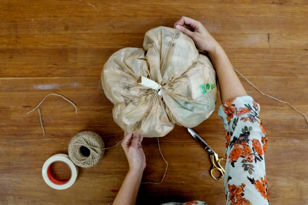 Wrap twine around the bag, pulling it tight to give the bag ribbed sections, like a pumpkin. Tie the ends of the twine so it’s secure.