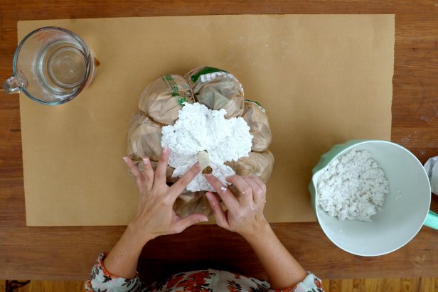 Working in small sections, form the paper mache onto the pumpkin. Cover the top half of the pumpkin, saving the stem until last so you can use it to turn the pumpkin around. Be sure to mold the paper mache into the ridges to keep the pumpkin shape. Set aside to let dry completely, which could take a full day or two.