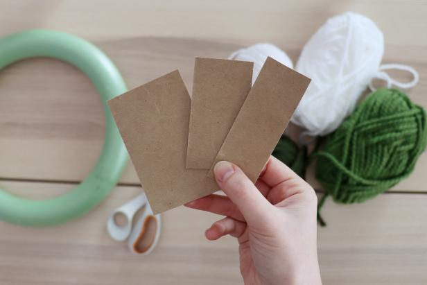 Cut cardboard into small rectangles that measure 1¼”, 1¾”, and 2¼” wide. These will be your patterns for the pom poms. Gather yarn in various colors and thicknesses.