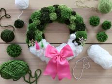 Green and white wreath with a pink bow and mini Christmas trees 