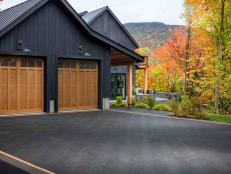 The large driveway leading up to the garage plays off the black siding in handsome dark gray stonework laid in a herringbone pattern for a timeless and polished look.