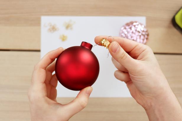 Remove the wire hanger and cap from a spare ornament. Remove the cap from the hot air balloon ornament. Use a 1/16” drill bit to drill two holes in the bottom of the ornament. Insert the wire hanger so that you can hang the ornament upside down.
