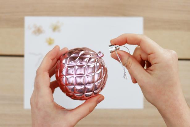 Remove the wire hanger and cap from a spare ornament. Remove the cap from the hot air balloon ornament. Use a 1/16” drill bit to drill two holes in the bottom of the ornament. Insert the wire hanger so that you can hang the ornament upside down.