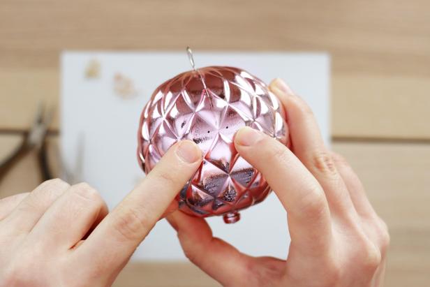 Mark two dots on the side of your ornament that are the same width apart as the width of your jump ring. Drill holes in those two spots. Open up the jump ring and insert it into one hole so that the end comes out of the other hole. Close it with jewelry pliers so you have a jump ring hanging off the side of the ornament. Repeat this to have four jump rings evenly spaced around the ornament. Add four smaller jump rings the same way to the bottom of the ornament.Note: Adding jump rings to the sides of the ornament is the trickiest part of this project, so you may want to practice on a spare ornament or drill slightly larger holes to give yourself more wiggle room.