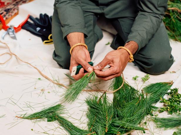 To make real garland you need jute twine, green floral wire on a paddle, pruning shearsand lots of greenery. Tip: Use pine to create the understructure and boxwood to make layers in the garland. First, use pruning shears to snip off small branches from the pine bundles. Then, add pieces of pine stems along a long piece of twine securing it with floral wire and pulling tightly as you go. Overlap the pine branches working down the twine to create one continual strand of uninterrupted garland. Leave a bit of twine at the end without greenery so you can tie all the components together.